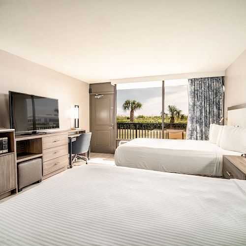 The image shows a hotel room with two beds, a TV, a desk, a chair, and a coffee maker, plus a scenic view through the large window.