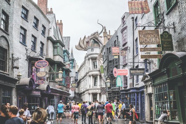 A bustling street with shops, a crowd of people, and a large, detailed dragon sculpture perched on a building.
