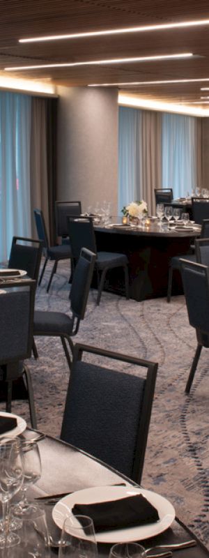 The image shows an elegant banquet hall setup with multiple round tables adorned with table settings, floral centerpieces, and glassware.
